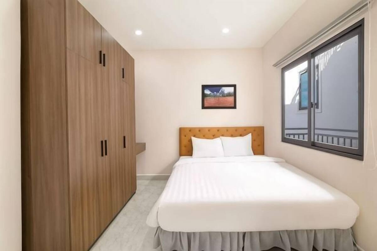A bedroom with a bed, wooden wardrobe, and a window with a view.