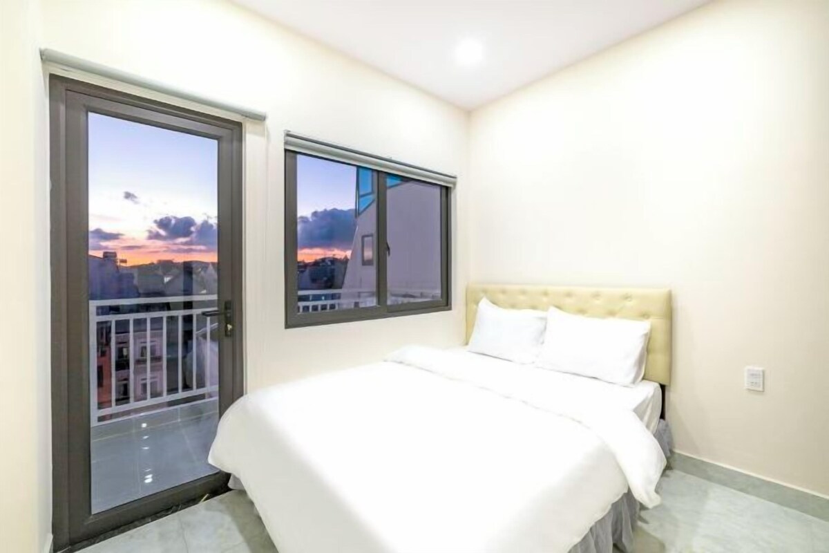 A bedroom with a bed, a window, and a door.
