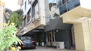 A modern building with a car parked in front, large windows, and outdoor air conditioning units. - SUGARLAND HOTEL & SUITES (Lagos)