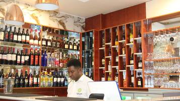 Zona de bar con estantes llenos de botellas de licores y copas de vino.