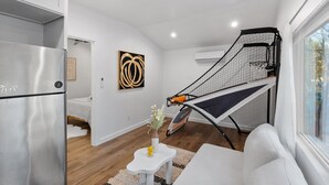 Een ruimtelijk ingerichte leefruimte met kitchenette, een bed, een klein tafeltje met een vaas en een raam met uitzicht.