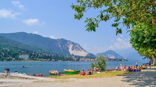 Une vue sur le lac, avec des bateaux, une plage de sable et des montagnes en arrière-plan.