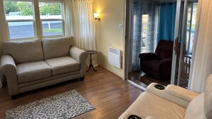 Una sala de estar con un sofá beige, un rug con diseño y un ventanal corredero que da a un balcón.
