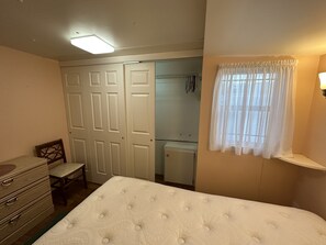 A bedroom with a bed, a dresser, a chair, a wardrobe, and a window with curtains. - Cozy little Lake Front Park Model (Port Richey)
