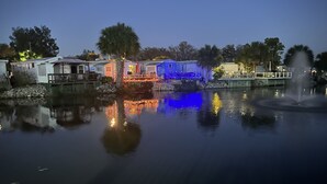 Vista al lago con una hilera de cabañas y una fuente.