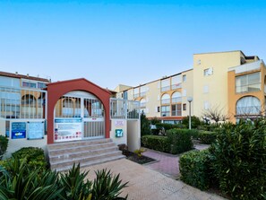 Stunning building with a red entrance archway, surrounded by lush greenery and a paved walkway.
