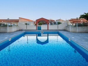 Relax by the pool surrounded by a low wall and a covered seating area.