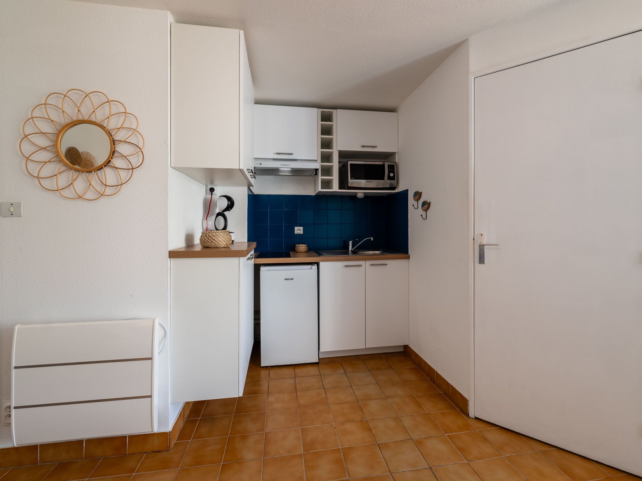 A compact kitchen with white cabinets, a microwave, and a small refrigerator.