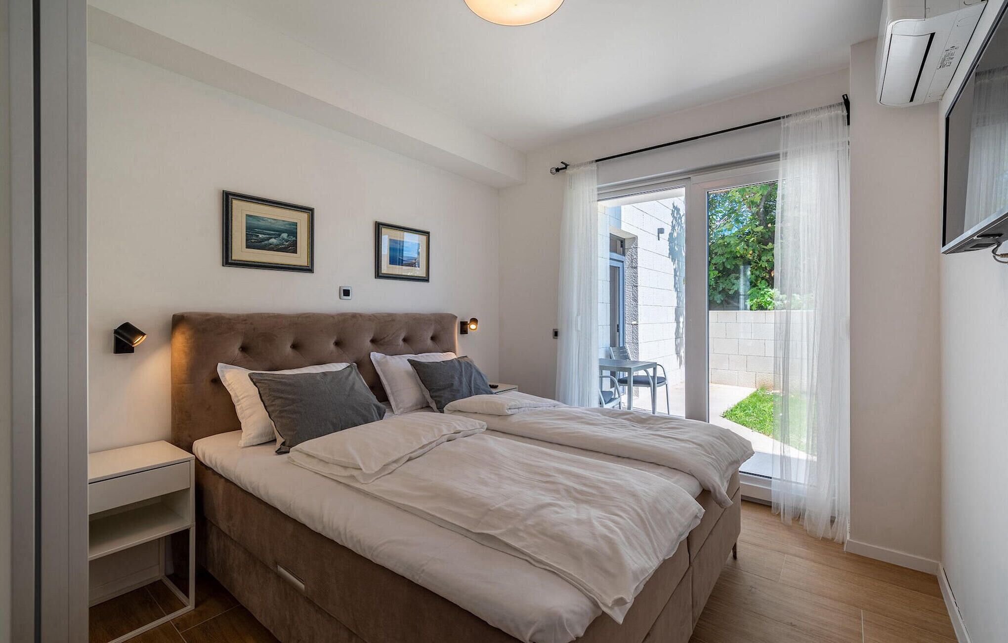Ein Schlafzimmer mit Bett, Nachttischen und Blick ins Freie.