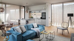 A modern living room with a blue sofa, a dining area with a round table, and a kitchen with white cabinets. - Stunning home in Vodnjan with sauna (Vodnjan)
