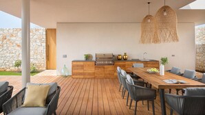 A modern outdoor kitchen with a wooden table and chairs, a grill, and hanging lights. - Stunning home in Vodnjan with sauna (Vodnjan)