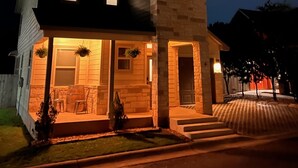 A two-story house with a stone facade, a front porch with outdoor seating, and a visible garage door.