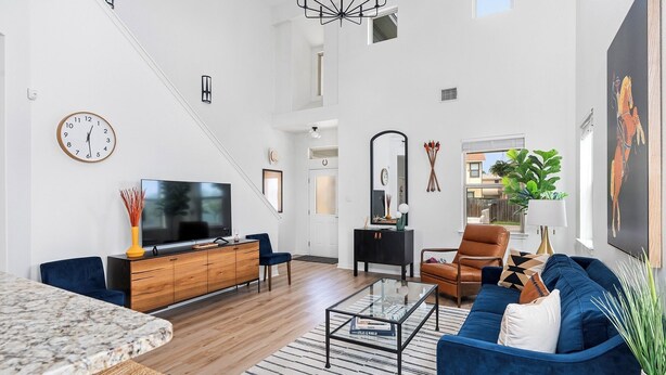 A modern living room with a large TV, a sofa, a coffee table, and a dining area with a marble table.