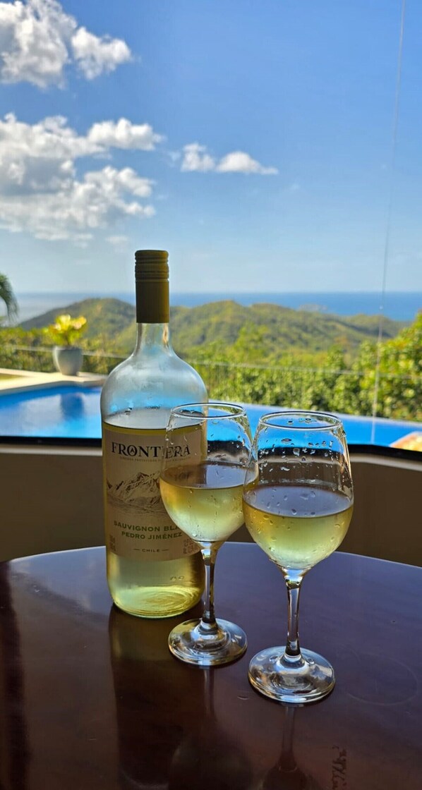 Una botella de vino Frontiera Sauvignon Blanc Pedro Jimenez y dos copas sobre una mesa con vistas a un paisaje montañoso.