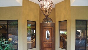 A hallway with a wooden door, large windows, and a chandelier. - Housekeeping•BBQ•Pool•4 TVs•Garden•Oceanview villa: Casa Sol Azul (Potrero)