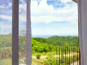 Un balcón con vistas a colinas verdes y un cielo despejado.