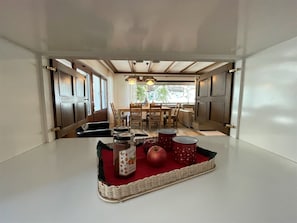 Un coin repas avec une table dressée pour deux personnes, agrémenté d'un plateau en osier contenant des bocaux et des pommes.