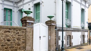 A white building with green shutters, a stone wall, and a white gate. - Villa Campo Bello by Interhome (Dinard)