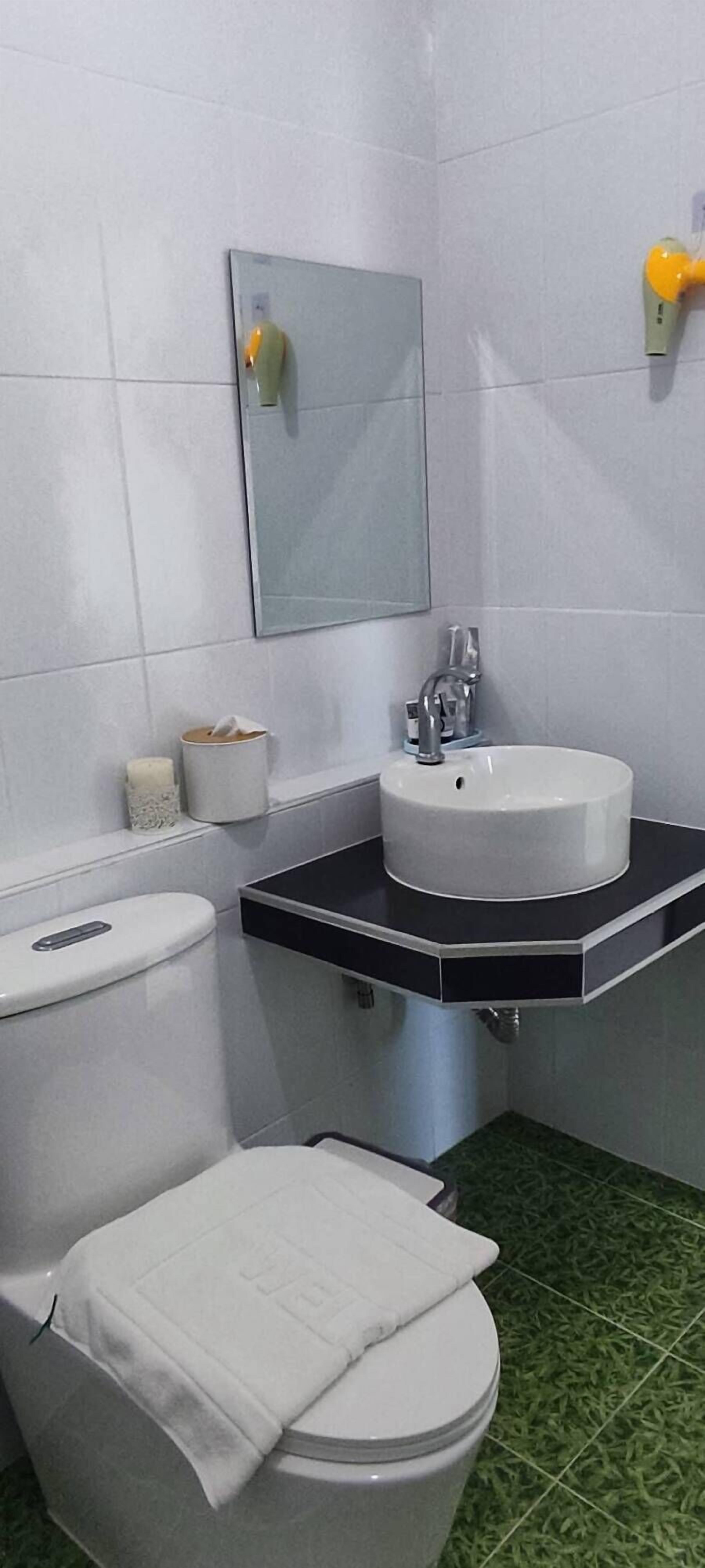 Un baño con inodoro, lavamanos y espejo.