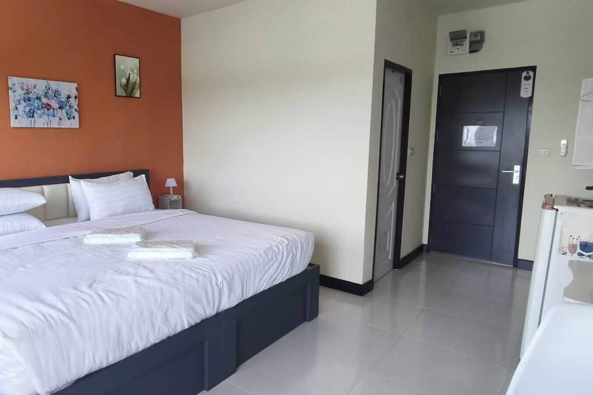 Habitación de hotel con una cama grande, una mesita de noche con lámpara y una puerta que da a un baño.