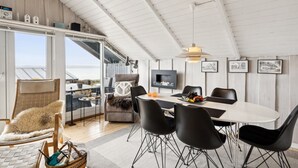 A spacious dining area with a large table, black chairs, and a modern pendant light.
