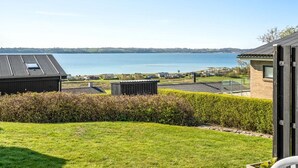 A residential area with a view of a lake, a grassy lawn, and a building with a sloped roof.