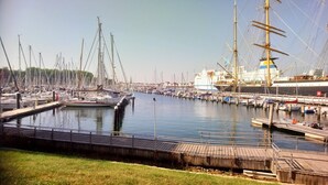 Un puerto deportivo con varias embarcaciones amarradas, un gran barco y una pasarela de madera.
