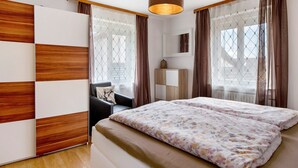 A bedroom with a bed, a chair, a wardrobe, and a hanging light fixture. - Holiday Apartment "Sink" with Private Terrace, Private Garden & Wi-Fi (Staufen)