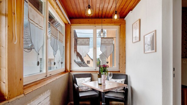A corner room with wooden walls, a table with two chairs, a bottle, and a glass. - Holiday Apartment "Sink" with Private Terrace, Private Garden & Wi-Fi (Staufen)