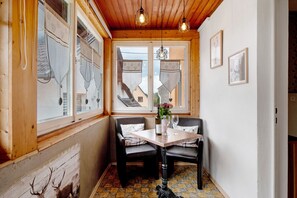 Una habitación de esquina con paredes de madera, una mesa con dos sillas, una botella y un vaso.