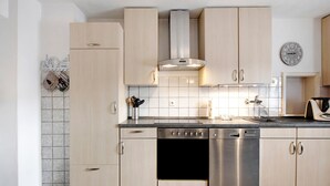 A modern kitchen with light wood cabinets, stainless steel appliances, and a tiled backsplash. - Holiday Apartment "Sink" with Private Terrace, Private Garden & Wi-Fi (Staufen)