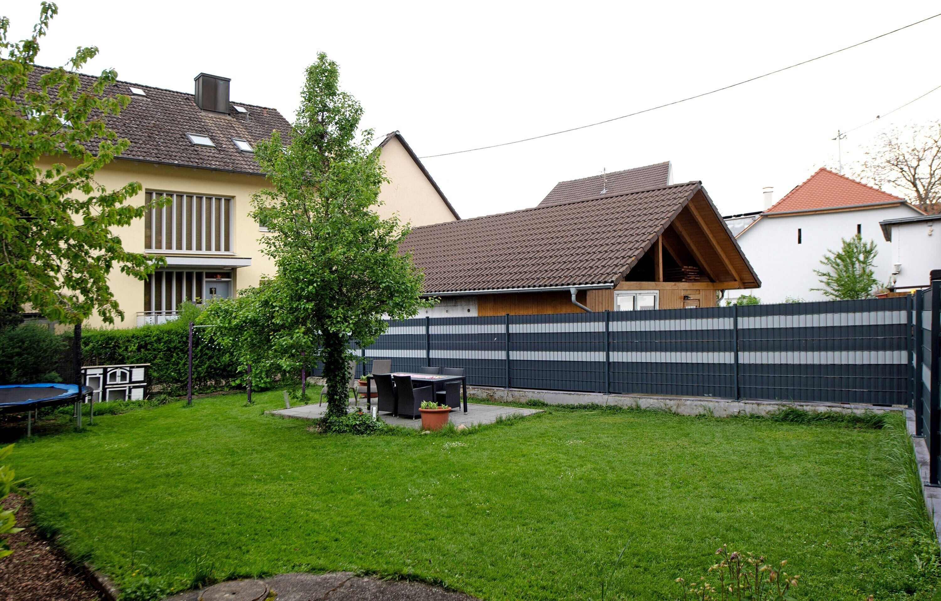 A residential area with a fenced yard, a trampoline, and a small table with chairs.