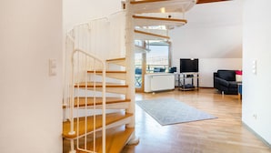 A modern interior with a spiral staircase, a flat-screen TV, and a sofa. - Apartment 'Ferienwohnung 2' with Shared Garden, Balcony and Wi-Fi (Hagnau am Bodensee)