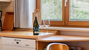 A kitchen counter with a wine bottle, two glasses, and a wicker basket. - Apartment 'Ferienwohnung 2' with Shared Garden, Balcony and Wi-Fi (Hagnau am Bodensee)