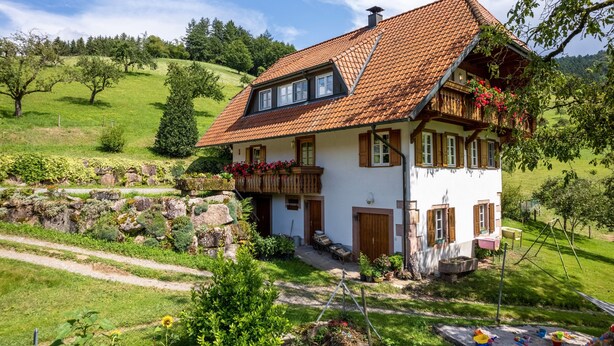 A traditional house with a sloped roof, a balcony with flowers, and a garden with a path leading to the entrance. - Holiday flat "DG", 85sqm, 2 bedrooms, max. 5 persons with panoramic view of nature (Nordrach)