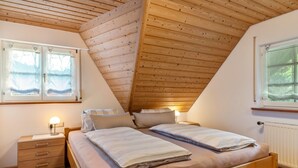 A bedroom with a sloped ceiling, two beds, a nightstand, and a window with a view. - Holiday flat "DG", 85sqm, 2 bedrooms, max. 5 persons with panoramic view of nature (Nordrach)