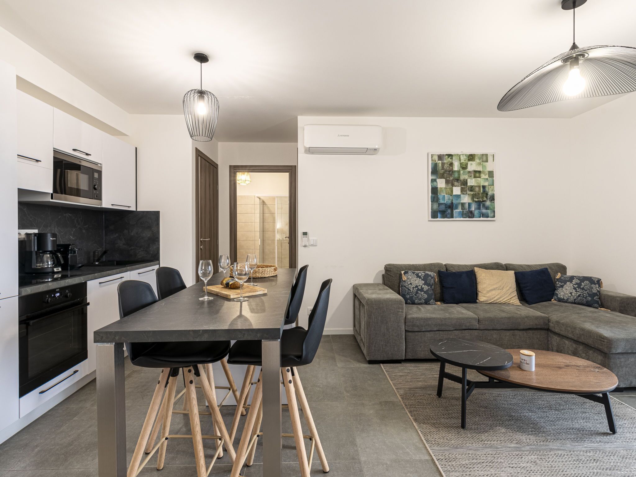 A modern kitchen with a dining table and chairs, a gray sofa, and a coffee table.