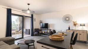 Een moderne woonkamer met een bank, een eettafel met stoelen, een televisie en een open haard.