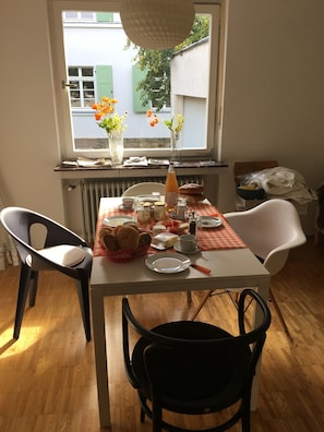 Une table à manger avec des chaises, une fenêtre avec des volets et un radiateur.