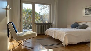 Quarto com uma cama, uma cadeira, uma janela e um radiador.