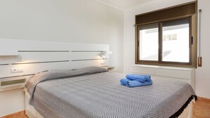 Ein Schlafzimmer mit Bett, Fenster und einer Wandleuchte.