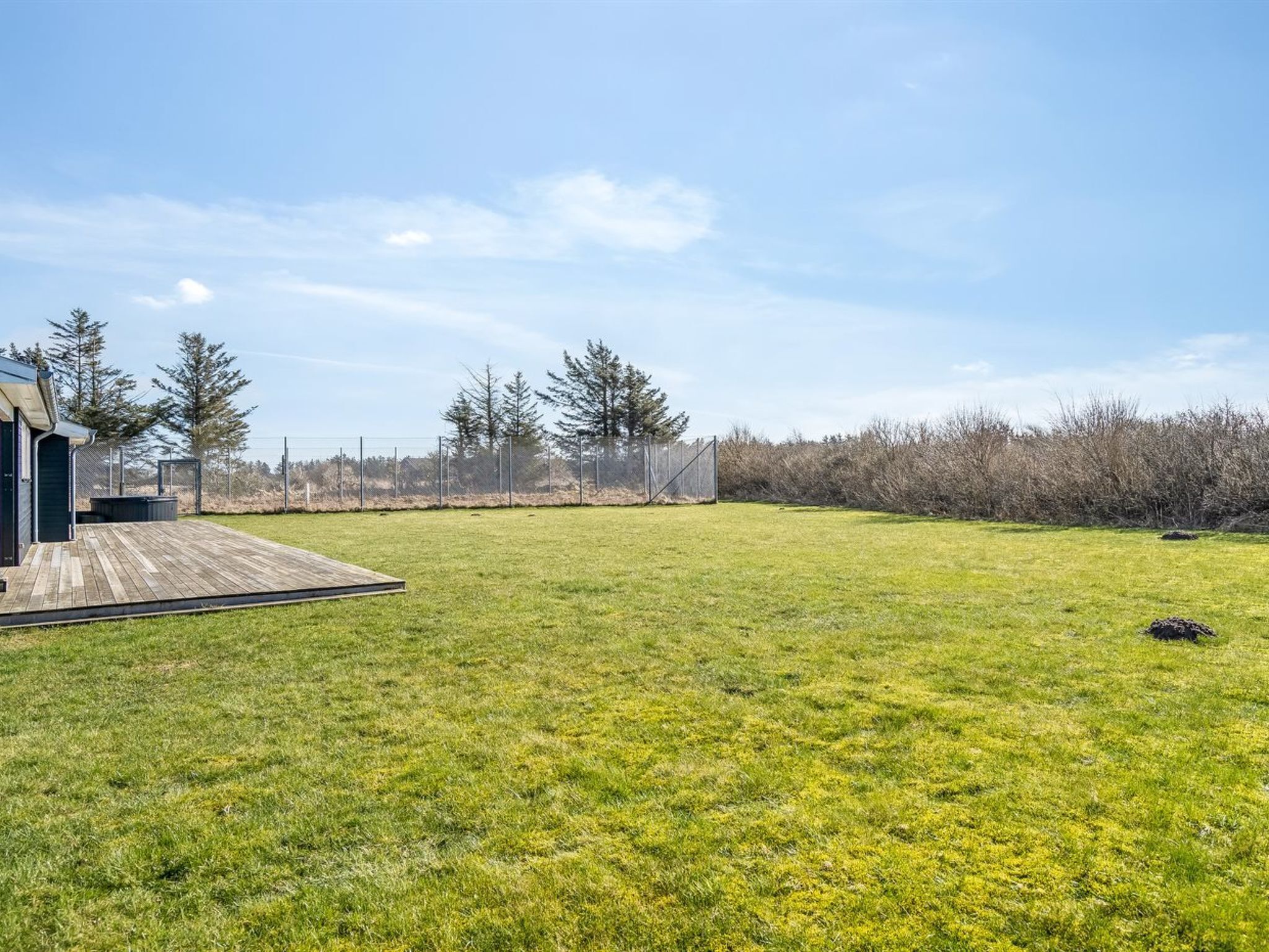 A grassy yard with a wooden deck and a building.
