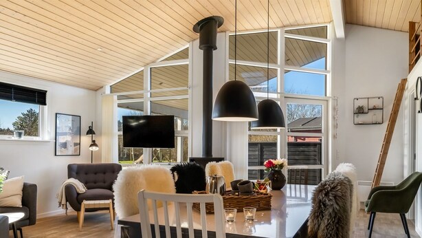A modern living room with a fireplace, large windows, and a dining area.