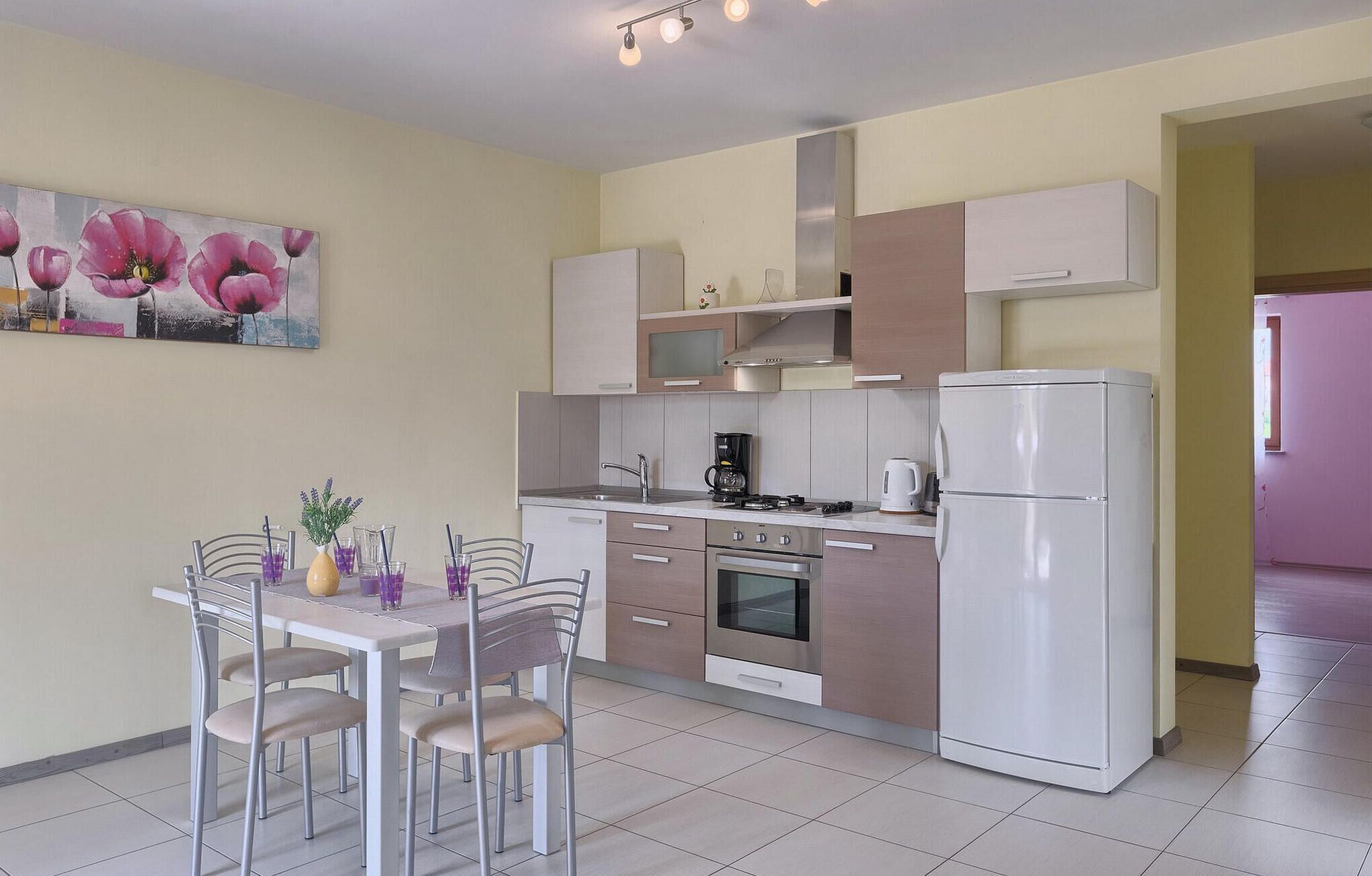 A modern kitchen with a dining area, featuring a refrigerator, stove, microwave, and a dining table with chairs.