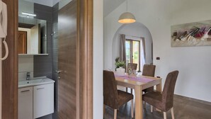 A modern dining area with a wooden table, brown upholstered chairs, and a pendant light.