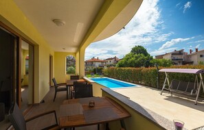 Un balcon avec une piscine, du mobilier d’extérieur et une vue sur les maisons voisines.