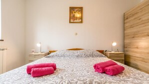 Hotellihuone, jossa on suuri sänky, kaksi yöpöytää valaisimineen, puinen sängynpääty ja seinällä oleva kehystetty kuva.