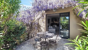 An outdoor patio with a round table and chairs, surrounded by lush greenery and purple flowering vines. - Lovely home in Saint-Laurent-de-la-Ca with WiFi (Saint-Laurent-de-la-Ca)