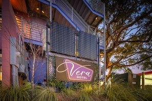 Vera Hotel's exterior features a prominent sign and a multi-storied building with a balcony.