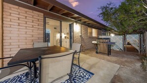 An outdoor patio with a brick wall, a table with chairs, and a grill area. - Cozy / Spotless / Central / Remodeled / 2 BR 1 BA (Tucson)